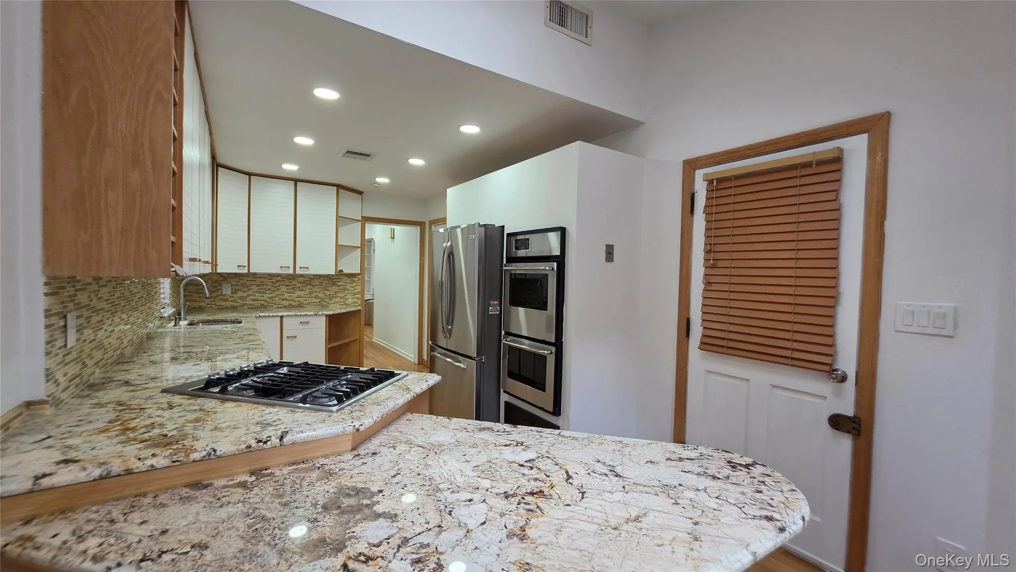 Gourmet kitchen featuring granite countertops, a built-in gas cooktop, stainless steel double ovens, a stainless steel refrigerator, and recessed lighting Gourmet kitchen featuring granite countertops, a built-in gas cooktop, stainless steel double ovens, a stainless steel refrigerator, and recessed lighting