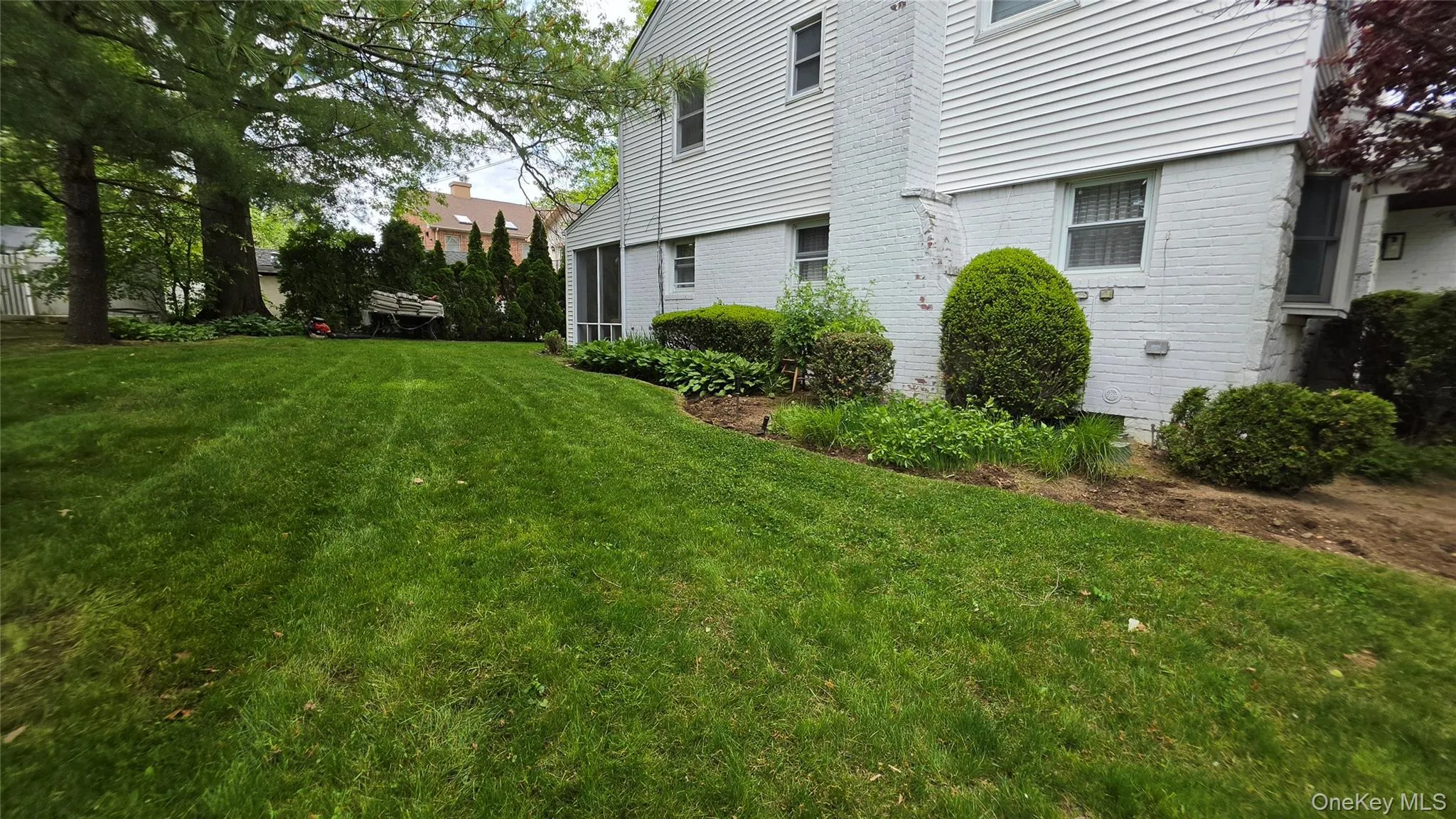 Expansive green lawn bordering a white brick and siding exterior Expansive green lawn bordering a white brick and siding exterior