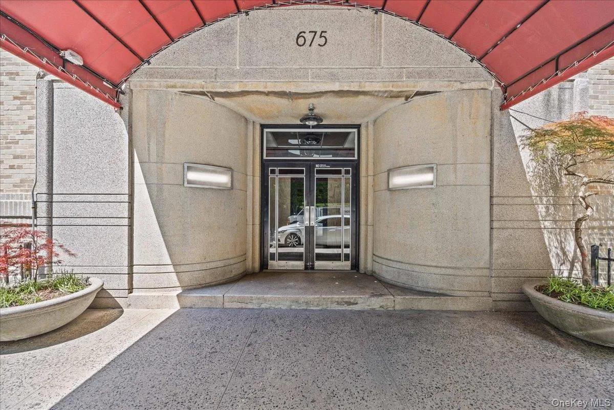Entryway featuring a red awning, stone facade, and glass-paneled double doors Entryway featuring a red awning, stone facade, and glass-paneled double doors