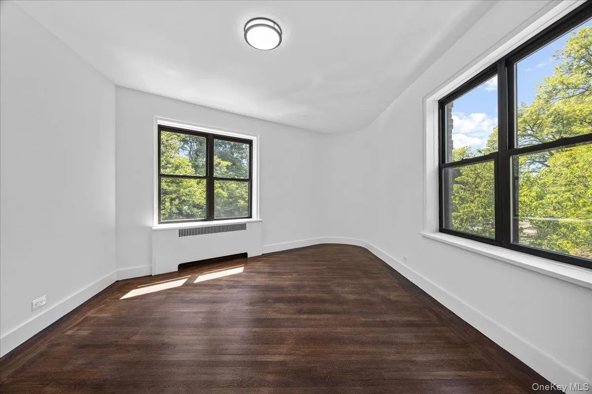 Bright interior space featuring dark hardwood flooring and multiple windows with black frames Bright interior space featuring dark hardwood flooring and multiple windows with black frames