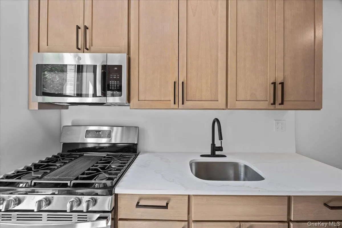 Newly renovated galley kitchen featuring light wood-finish cabinetry, light quartz countertops, and tile flooring Newly renovated galley kitchen featuring light wood-finish cabinetry, light quartz countertops, and tile flooring