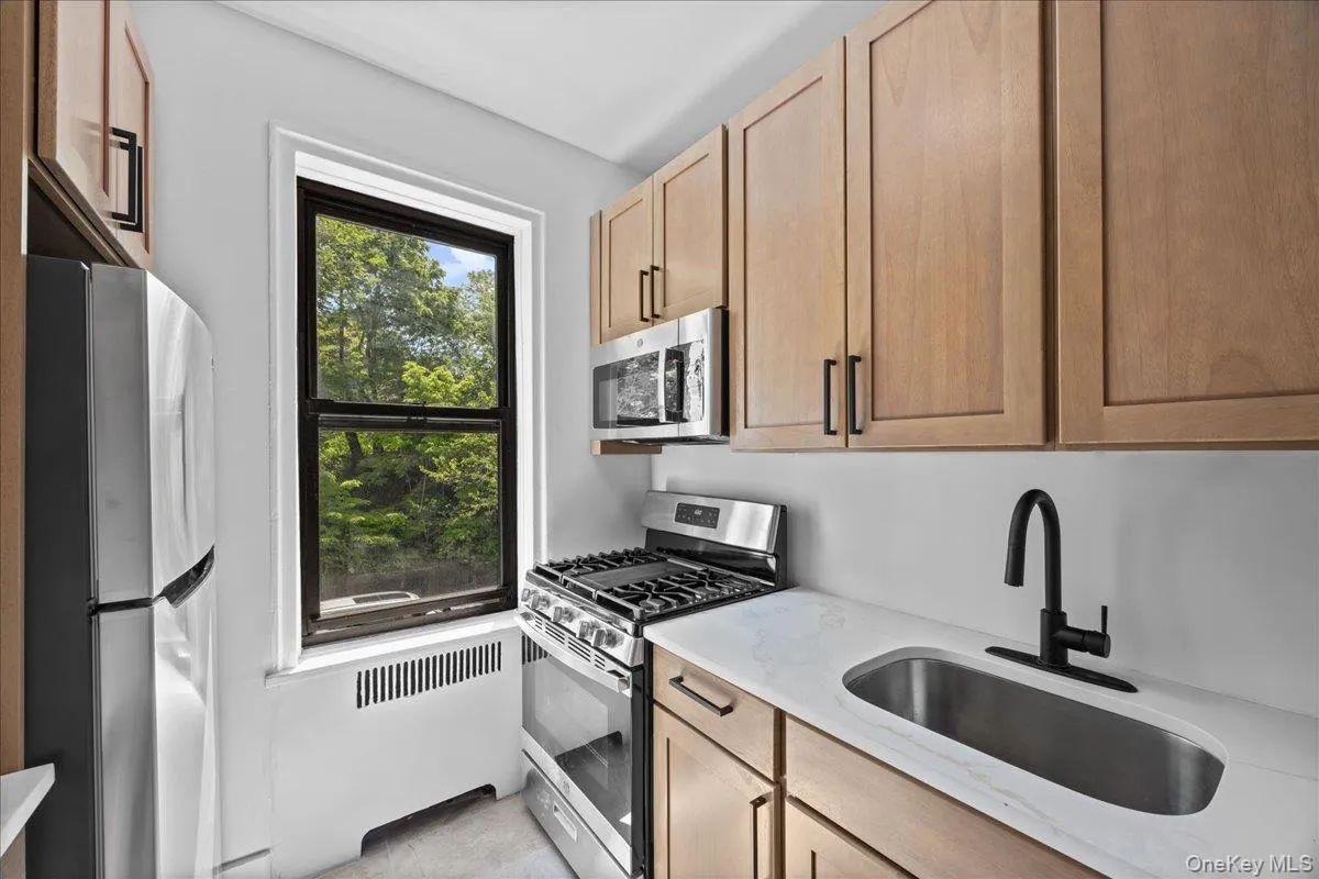 Newly renovated galley kitchen featuring light wood-finish cabinetry, light quartz countertops, and tile flooring Newly renovated galley kitchen featuring light wood-finish cabinetry, light quartz countertops, and tile flooring