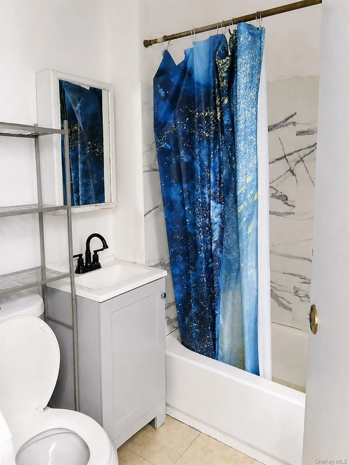 Bathroom featuring a white bathtub, a pedestal sink with matte black faucet, a built-in medicine cabinet, and tiled walls Bathroom featuring a white bathtub, a pedestal sink with matte black faucet, a built-in medicine cabinet, and tiled walls
