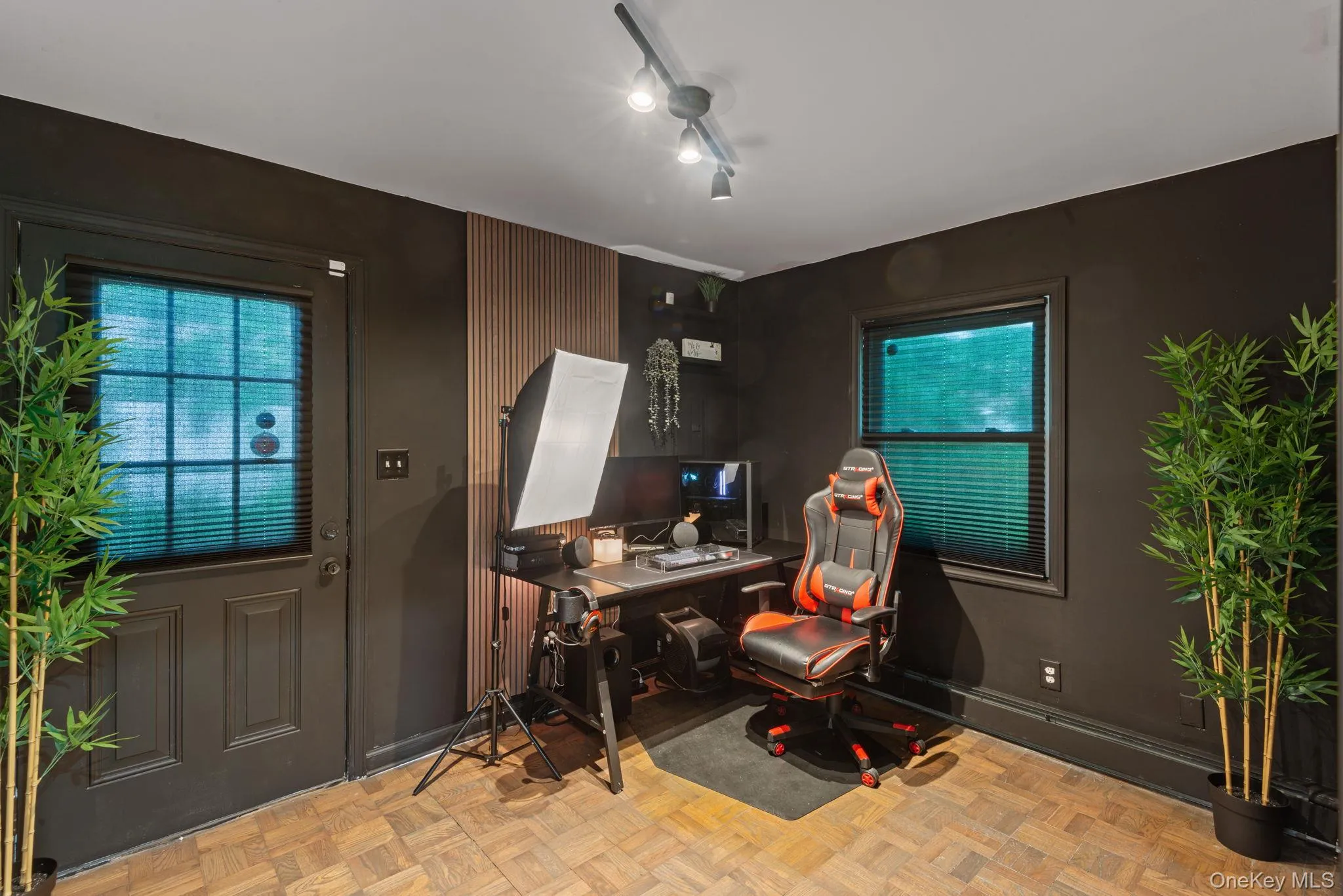 Office or multipurpose room featuring parquet wood-finish flooring, dark-painted walls, and a track lighting fixture Office or multipurpose room featuring parquet wood-finish flooring, dark-painted walls, and a track lighting fixture