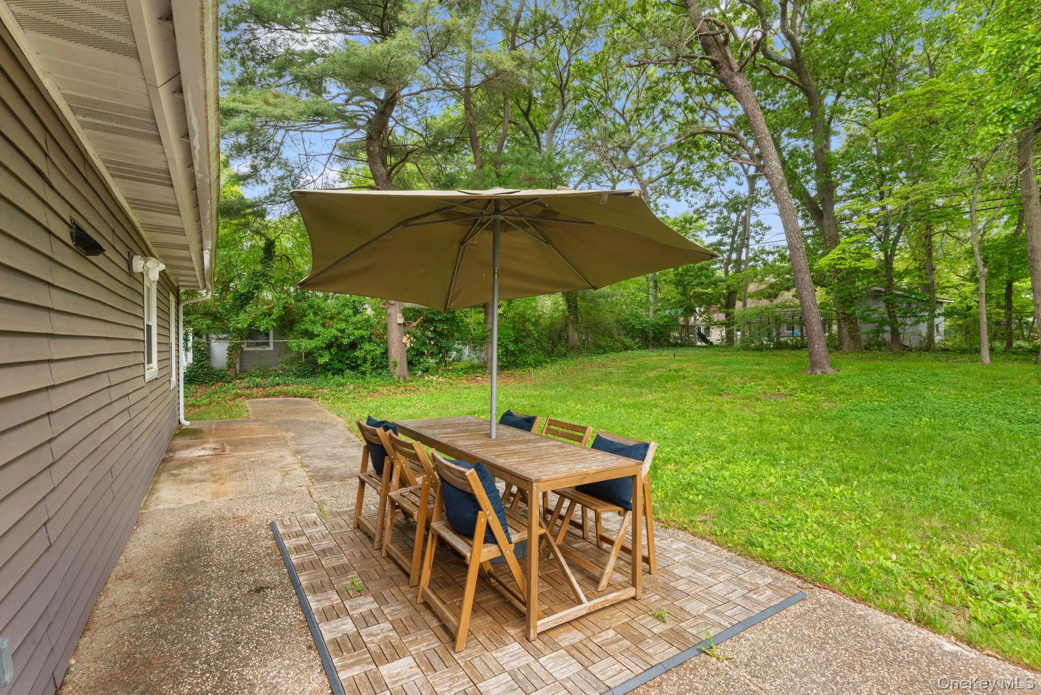 Concrete patio in the backyard with privacy fencing and mature trees Concrete patio in the backyard with privacy fencing and mature trees