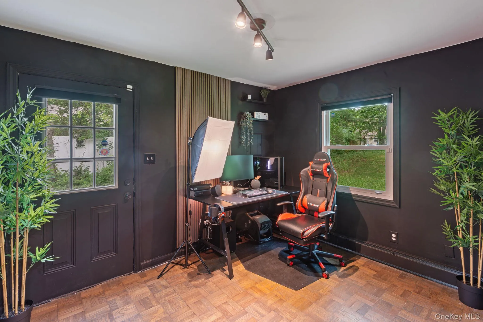 Office or multipurpose room featuring parquet wood-finish flooring, dark-painted walls, and a track lighting fixture Office or multipurpose room featuring parquet wood-finish flooring, dark-painted walls, and a track lighting fixture