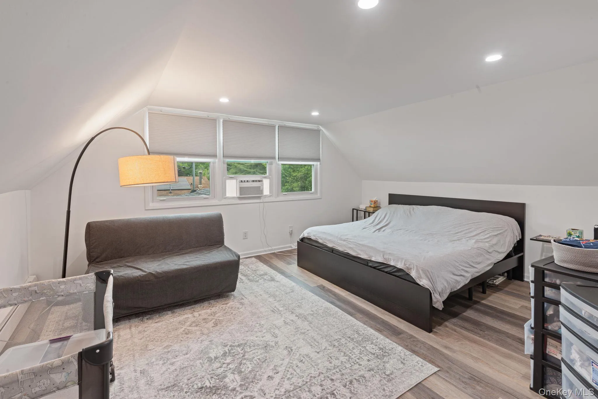 Spacious primary bedroom featuring sloped ceilings, recessed lighting, and wood-finish flooring Spacious primary bedroom featuring sloped ceilings, recessed lighting, and wood-finish flooring