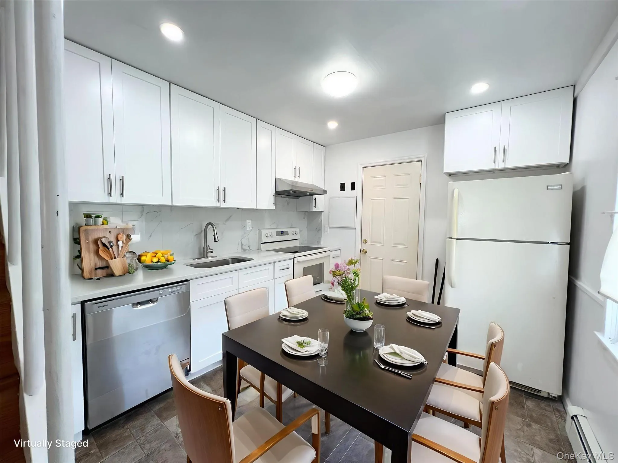Kitchen with white appliances, decorative backsplash, white cabinets, light countertops, and a baseboard heating unit Kitchen with white appliances, decorative backsplash, white cabinets, light countertops, and a baseboard heating unit