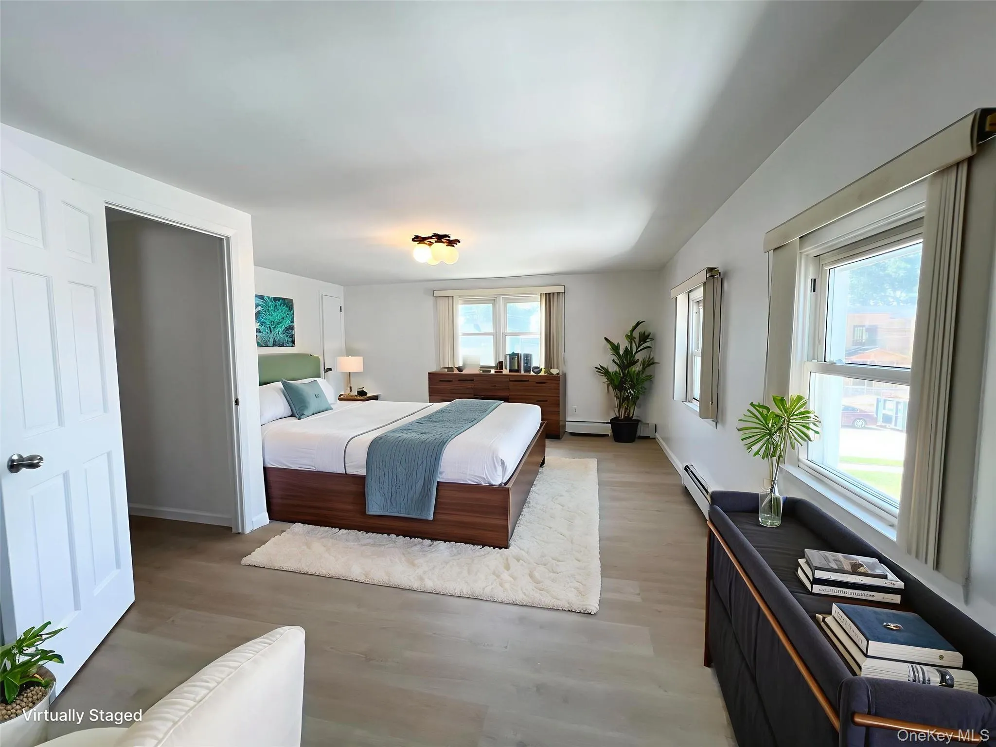 Bedroom with light wood-type flooring, multiple windows, and baseboard heating Bedroom with light wood-type flooring, multiple windows, and baseboard heating