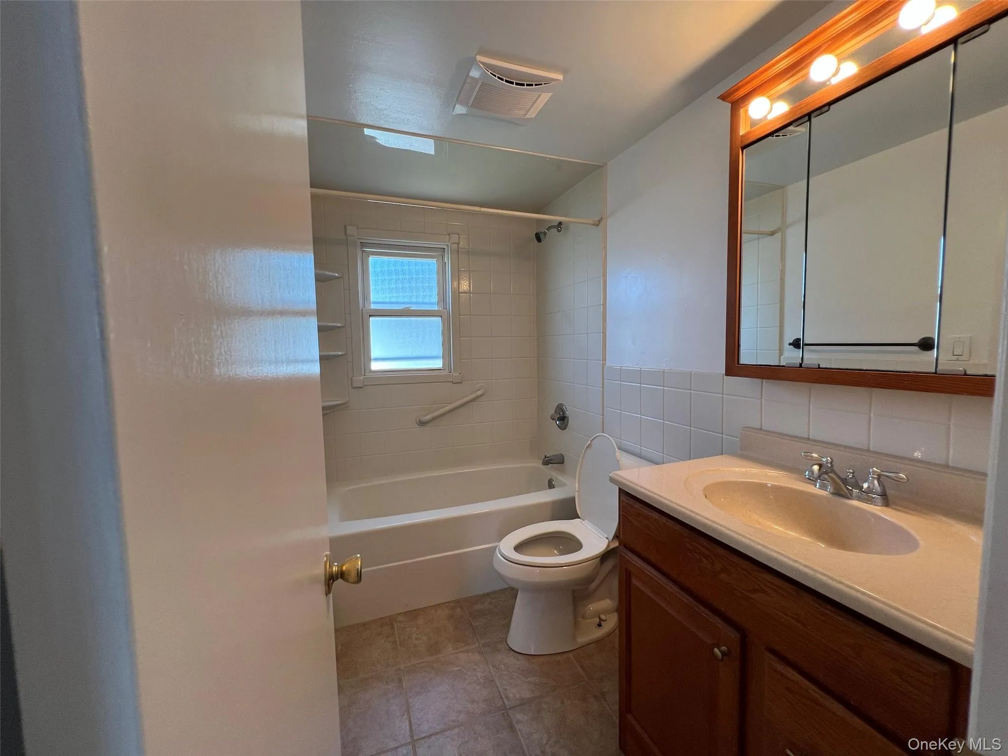 Full bath featuring tile walls, bathtub / shower combination, vanity, and tile patterned flooring Full bath featuring tile walls, bathtub / shower combination, vanity, and tile patterned flooring