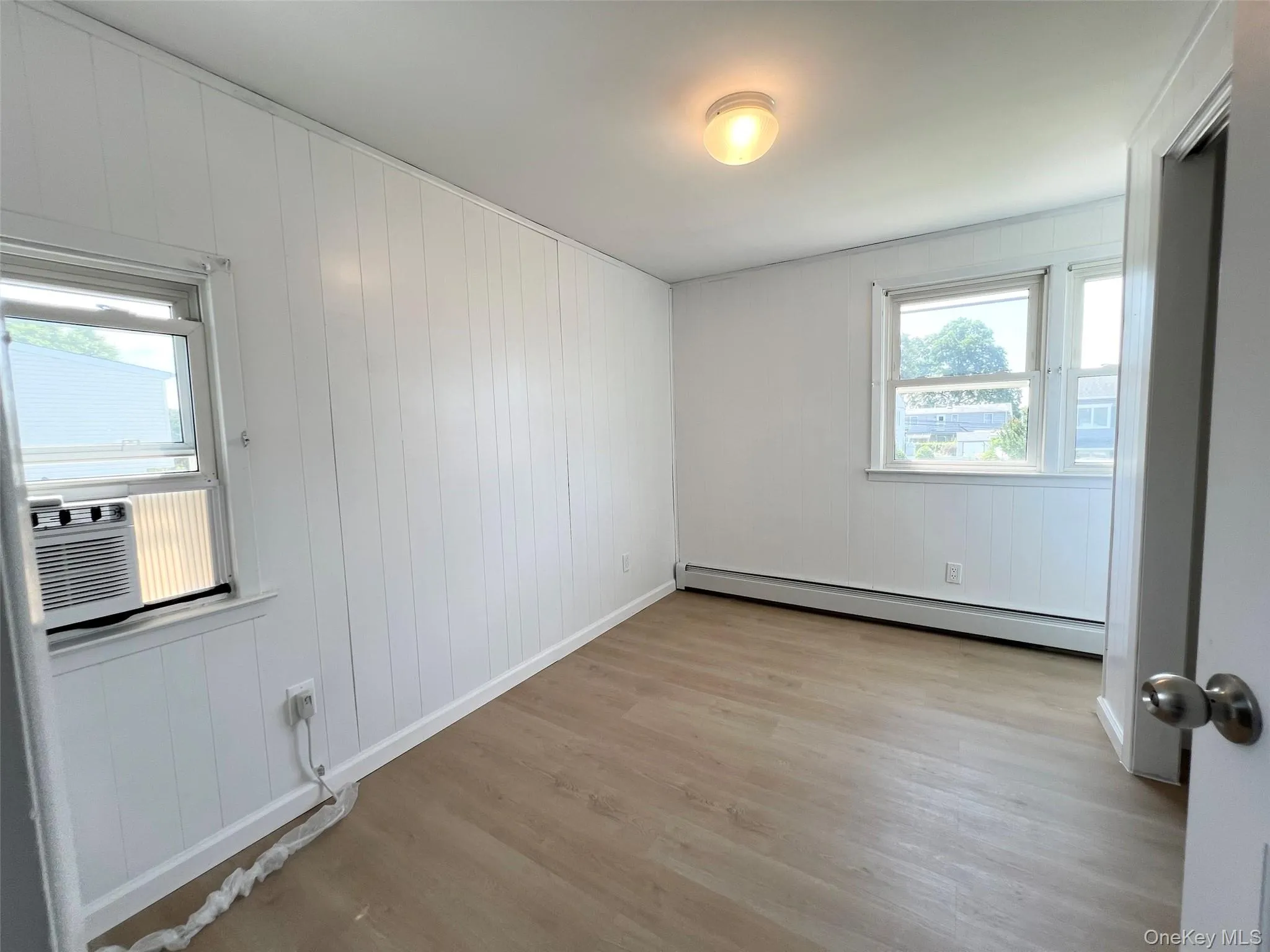 Empty room featuring light wood finished floors and a baseboard radiator Empty room featuring light wood finished floors and a baseboard radiator