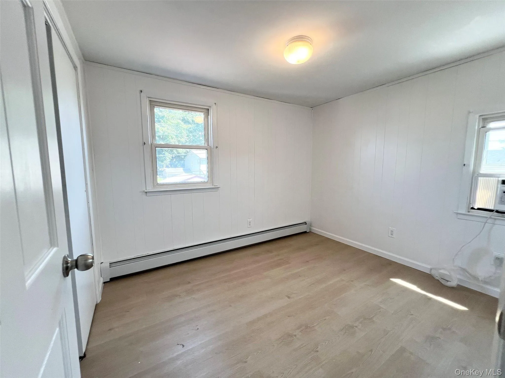 Spare room with a baseboard radiator, plenty of natural light, and light wood-style flooring Spare room with a baseboard radiator, plenty of natural light, and light wood-style flooring