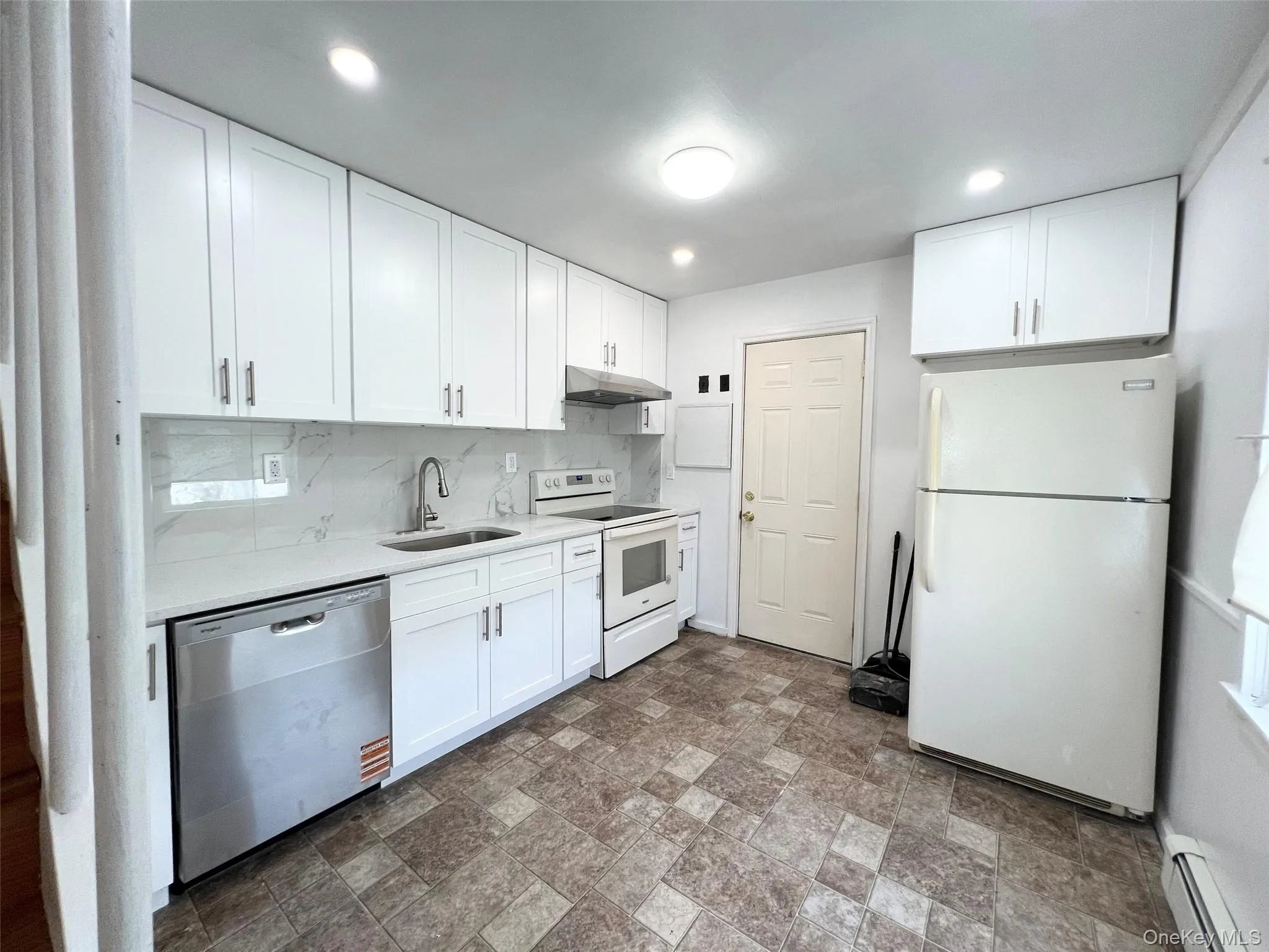 Kitchen featuring white appliances, light countertops, a baseboard heating unit, white cabinets, and recessed lighting Kitchen featuring white appliances, light countertops, a baseboard heating unit, white cabinets, and recessed lighting