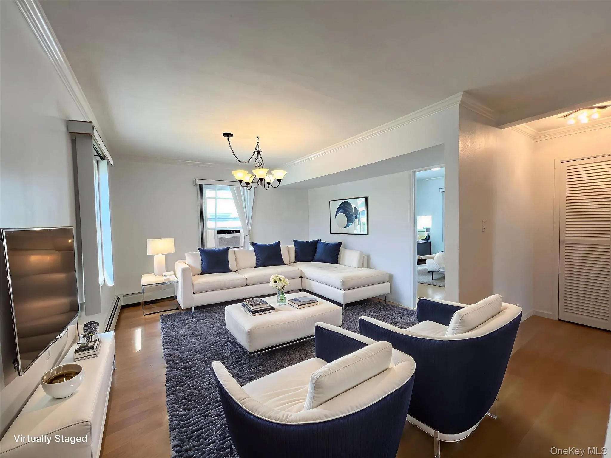 Living room with crown molding, wood finished floors, a chandelier, and a baseboard heating unit Living room with crown molding, wood finished floors, a chandelier, and a baseboard heating unit
