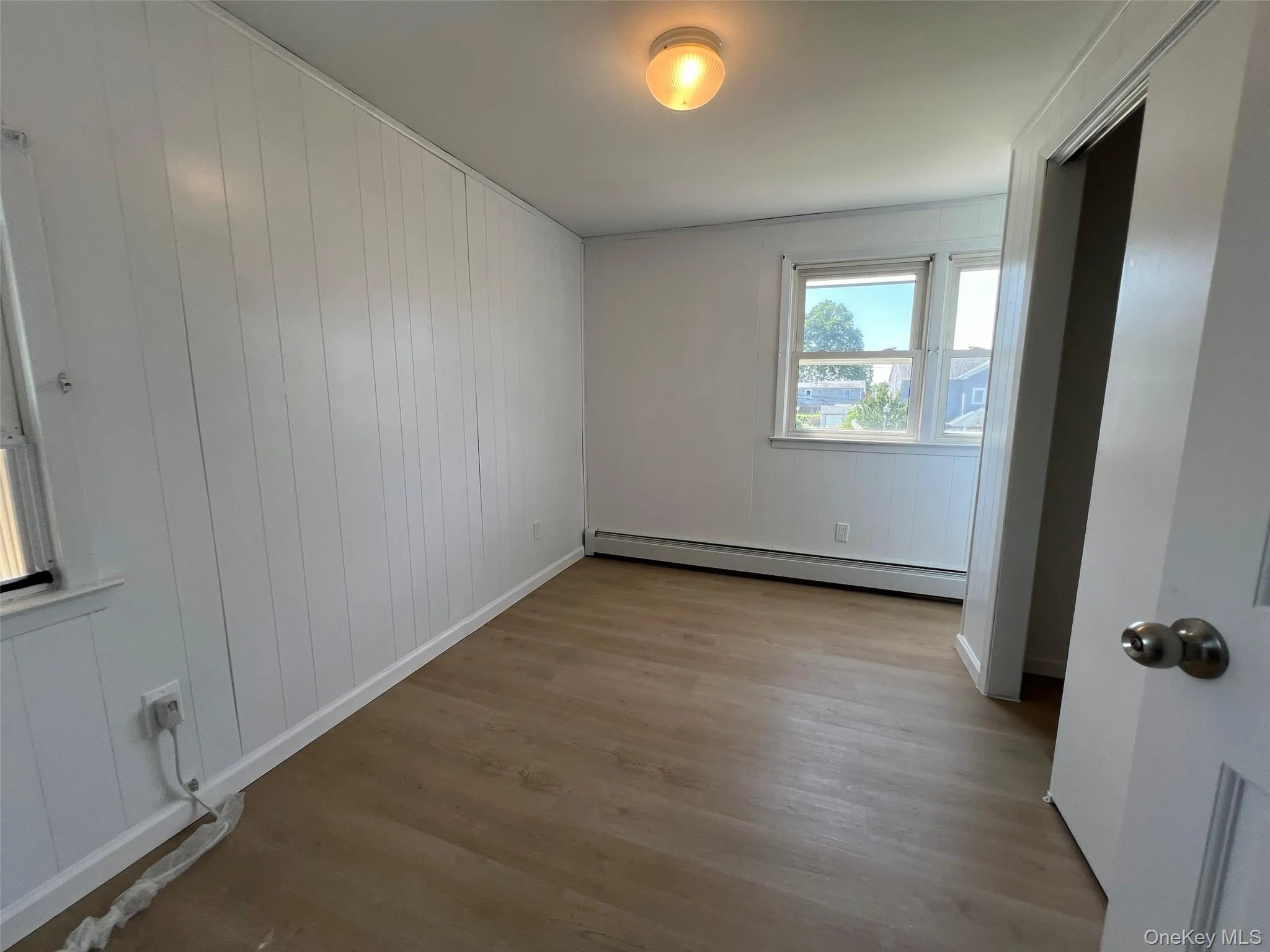 Empty room with baseboard heating and wood finished floors Empty room with baseboard heating and wood finished floors