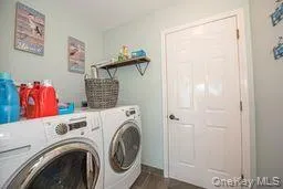 Washroom with laundry area, dark wood finished floors, and washing machine and clothes dryer Washroom with laundry area, dark wood finished floors, and washing machine and clothes dryer