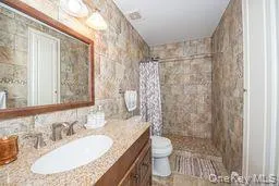 Bathroom with a tile shower, vanity, and toilet Bathroom with a tile shower, vanity, and toilet