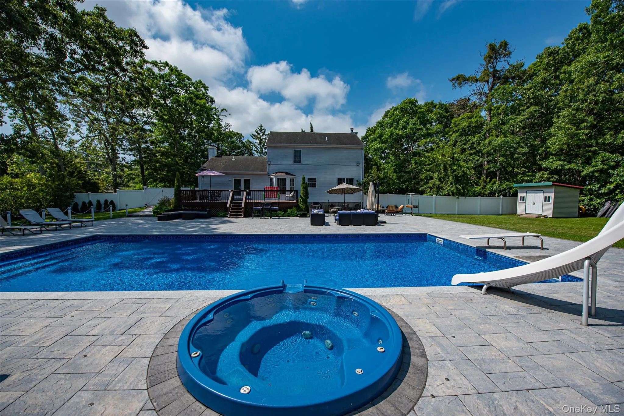 View of swimming pool with a fenced backyard, an outdoor structure, a wooden deck, and an in ground hot tub View of swimming pool with a fenced backyard, an outdoor structure, a wooden deck, and an in ground hot tub