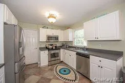 Kitchen with appliances with stainless steel finishes, dark countertops, and white cabinets Kitchen with appliances with stainless steel finishes, dark countertops, and white cabinets