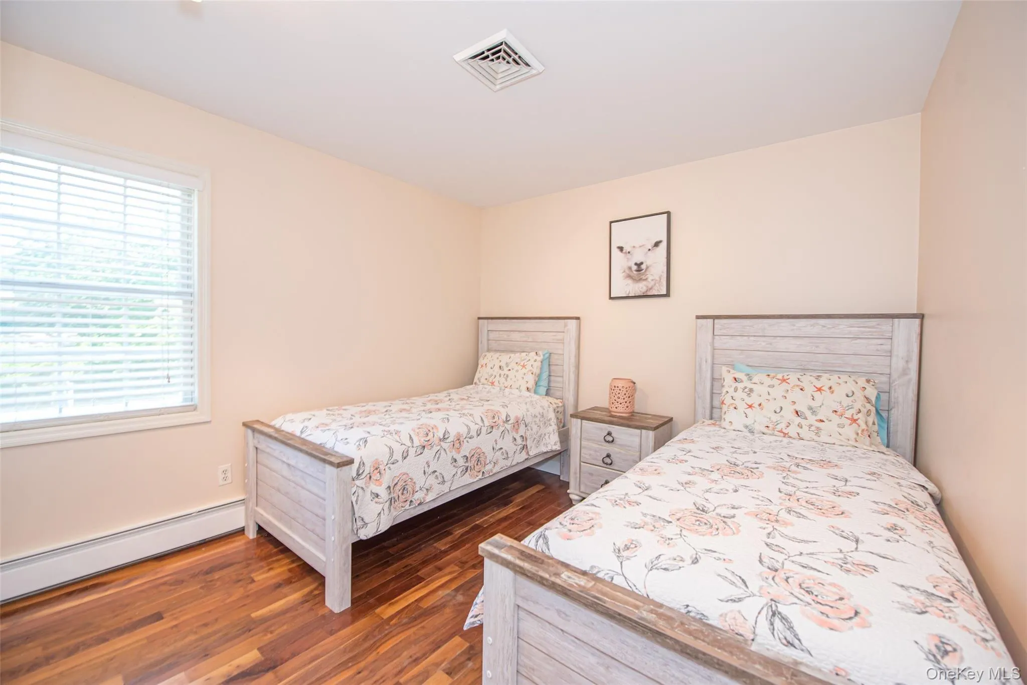 Bedroom with a baseboard heating unit, visible vents, and wood finished floors Bedroom with a baseboard heating unit, visible vents, and wood finished floors