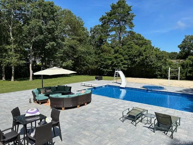 Outdoor pool with a water slide, an in ground hot tub, an outdoor living space, a yard, and a patio area Outdoor pool with a water slide, an in ground hot tub, an outdoor living space, a yard, and a patio area
