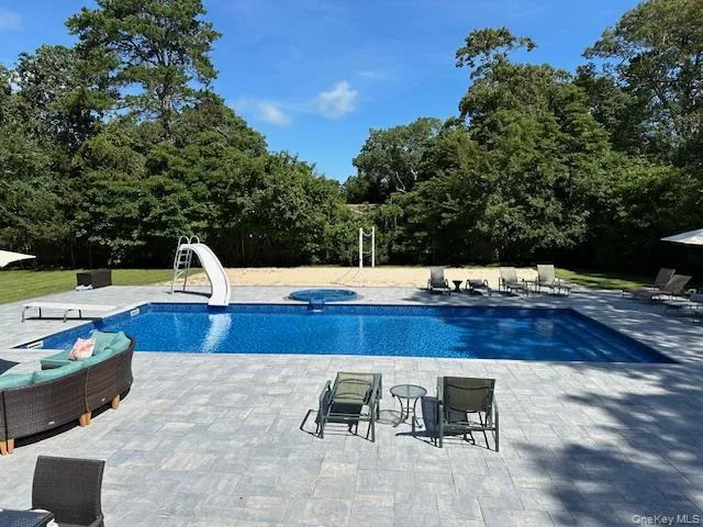 Outdoor pool with an in ground hot tub, a water slide, and a patio area Outdoor pool with an in ground hot tub, a water slide, and a patio area