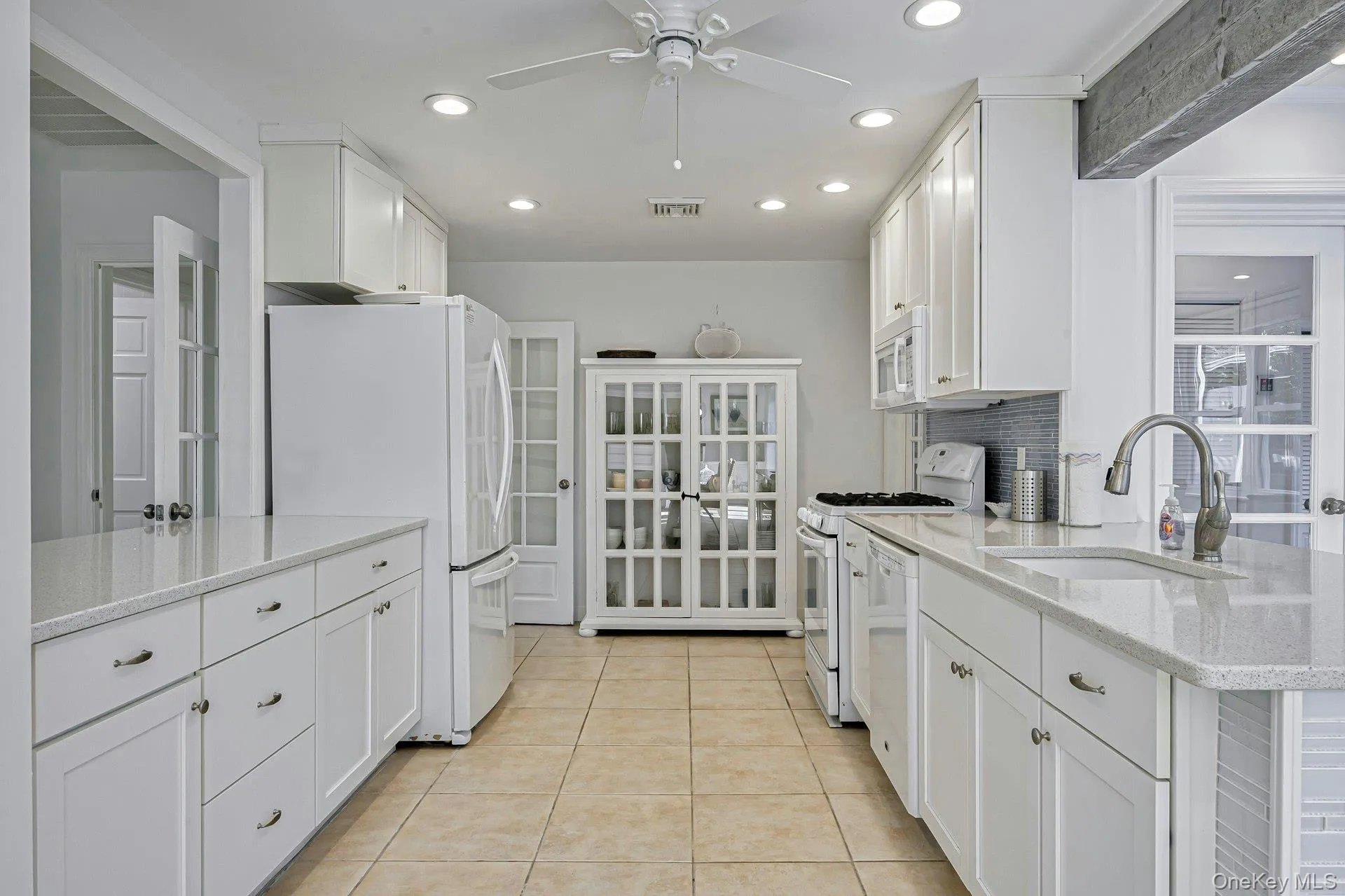 Modern kitchen featuring white cabinetry, light-toned countertops, and tile flooring Modern kitchen featuring white cabinetry, light-toned countertops, and tile flooring