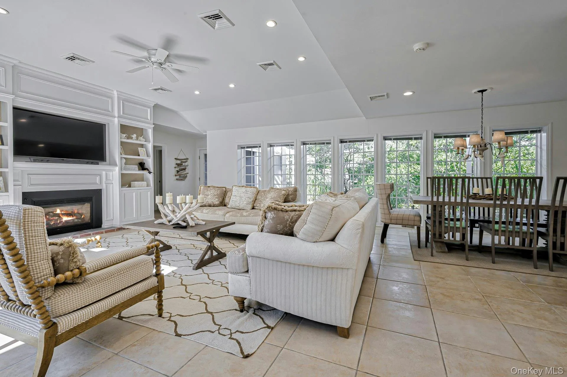 Open concept living space featuring a built-in media center with fireplace, recessed lighting, a ceiling fan, and light-toned tile flooring Open concept living space featuring a built-in media center with fireplace, recessed lighting, a ceiling fan, and light-toned tile flooring