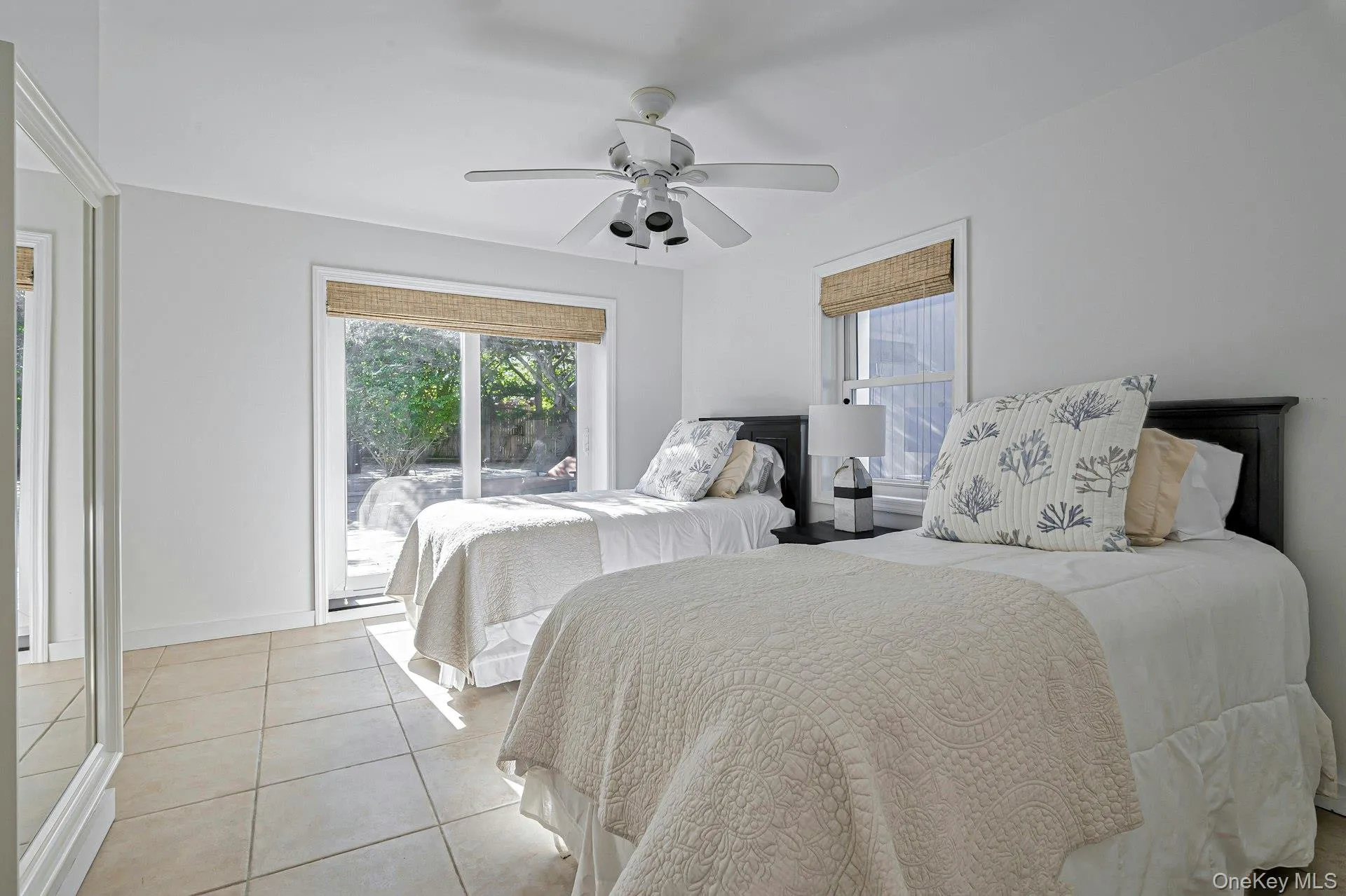 Bright room featuring neutral-toned tile flooring, a white ceiling fan, and white walls Bright room featuring neutral-toned tile flooring, a white ceiling fan, and white walls