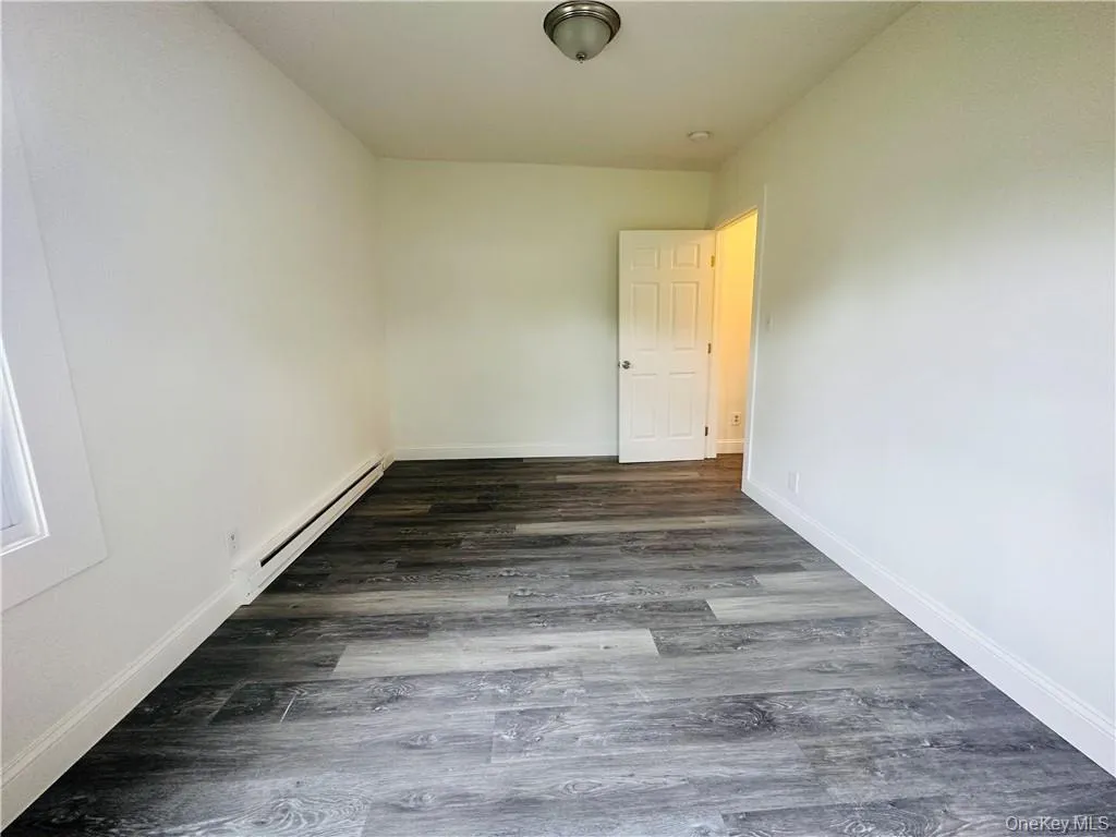 Spare room with baseboard heating and dark hardwood / wood-style flooring Spare room with baseboard heating and dark hardwood / wood-style flooring