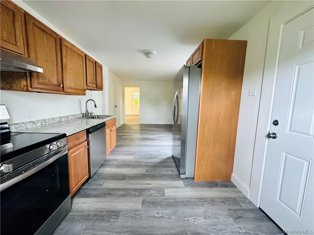 Kitchen with hardwood / wood-style floors, sink, and appliances with stainless steel finishes Kitchen with hardwood / wood-style floors, sink, and appliances with stainless steel finishes