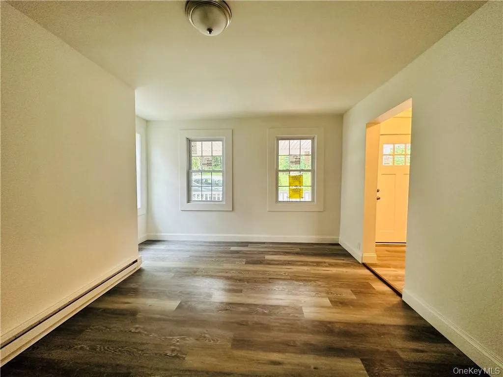 Unfurnished room featuring baseboard heating and hardwood / wood-style flooring Unfurnished room featuring baseboard heating and hardwood / wood-style flooring