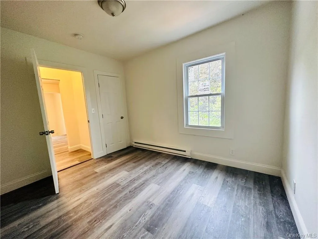 Spare room with baseboard heating and hardwood / wood-style floors Spare room with baseboard heating and hardwood / wood-style floors