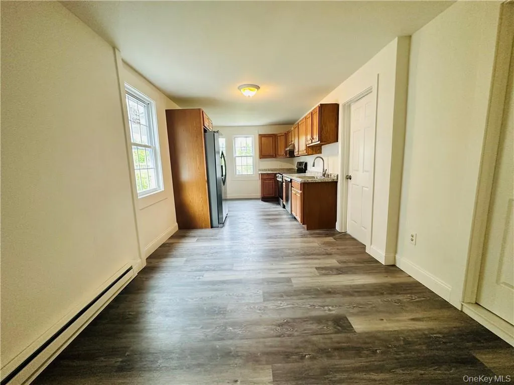 Kitchen featuring hardwood / wood-style floors, electric stove, sink, a baseboard radiator, and stainless steel refrigerator Kitchen featuring hardwood / wood-style floors, electric stove, sink, a baseboard radiator, and stainless steel refrigerator