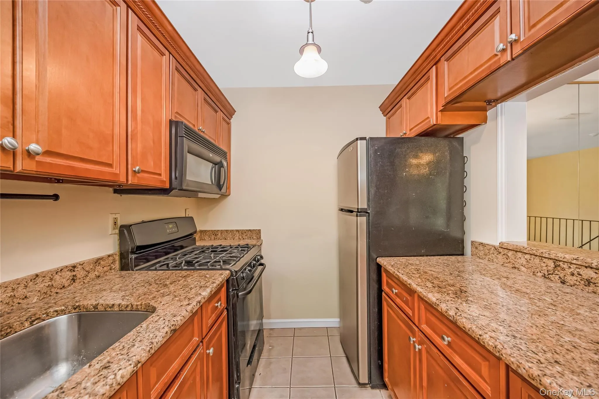 Kitchen featuring wood cabinetry, granite countertops, and tile flooring Kitchen featuring wood cabinetry, granite countertops, and tile flooring