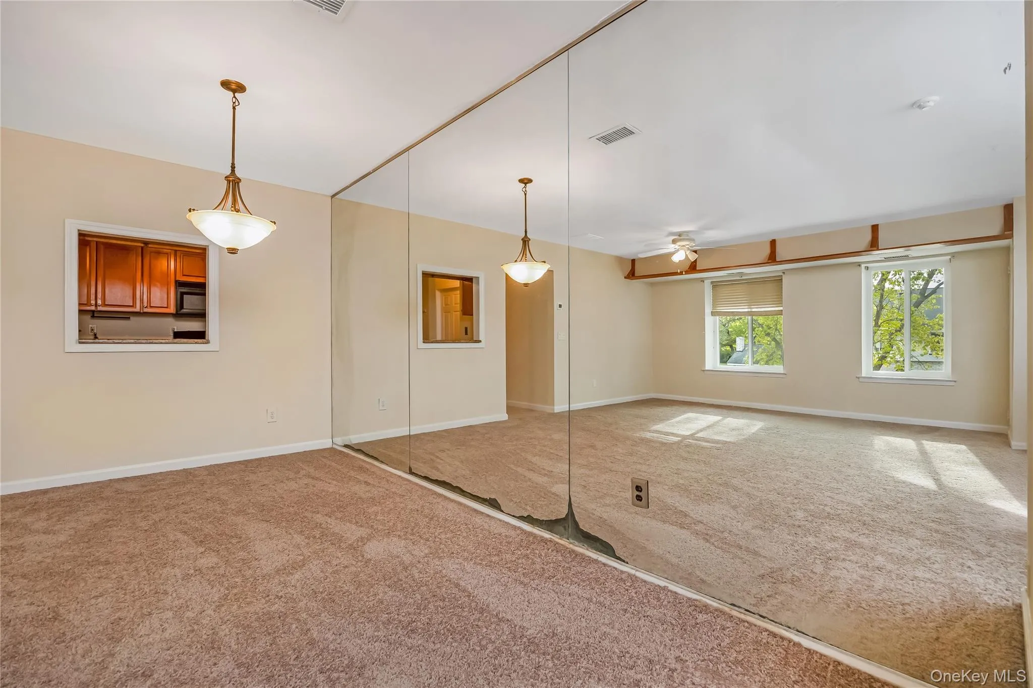 Expansive room featuring wall-to-wall carpeting and a full mirrored wall Expansive room featuring wall-to-wall carpeting and a full mirrored wall
