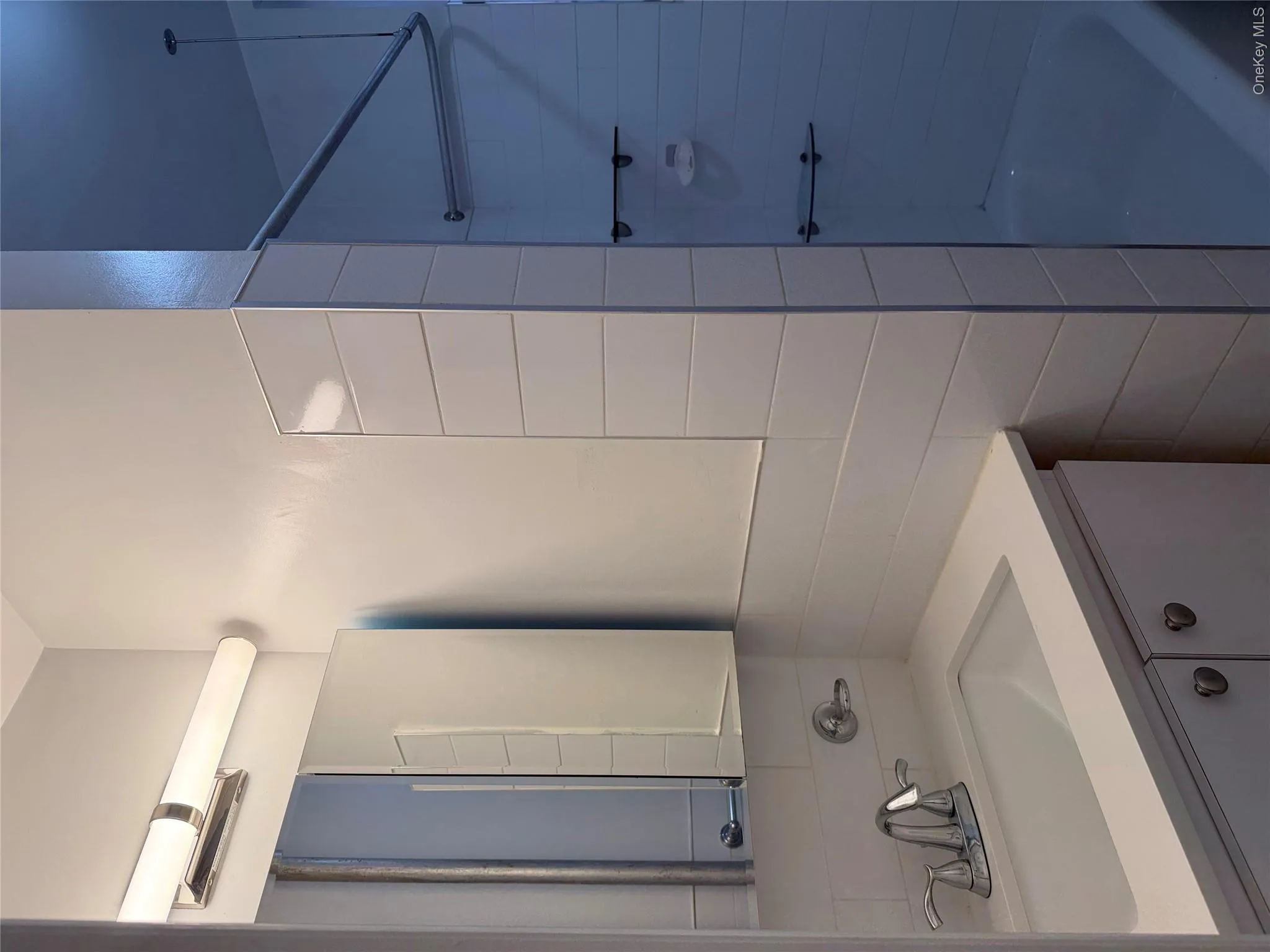 Bathroom vanity featuring a chrome faucet with a white integrated sink, set within a white cabinet with dark hardware Bathroom vanity featuring a chrome faucet with a white integrated sink, set within a white cabinet with dark hardware