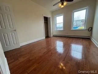Unfurnished bedroom with a baseboard radiator, ceiling fan, baseboards, and wood finished floors Unfurnished bedroom with a baseboard radiator, ceiling fan, baseboards, and wood finished floors