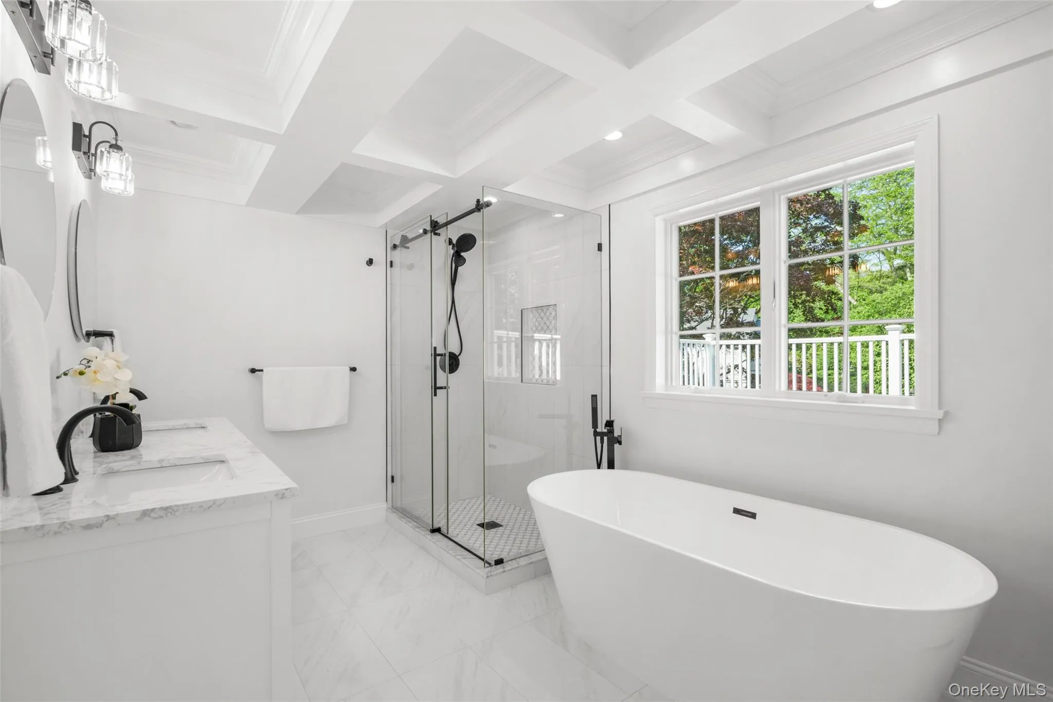 Newly renovated primary bath with soaking tub, glass-enclosed shower and treetop views. Newly renovated primary bath with soaking tub, glass-enclosed shower and treetop views.