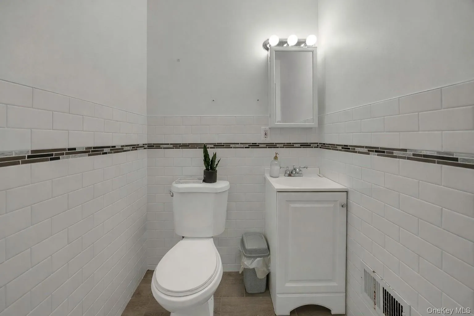 Half bath with vanity, a wainscoted wall, and tile walls Half bath with vanity, a wainscoted wall, and tile walls