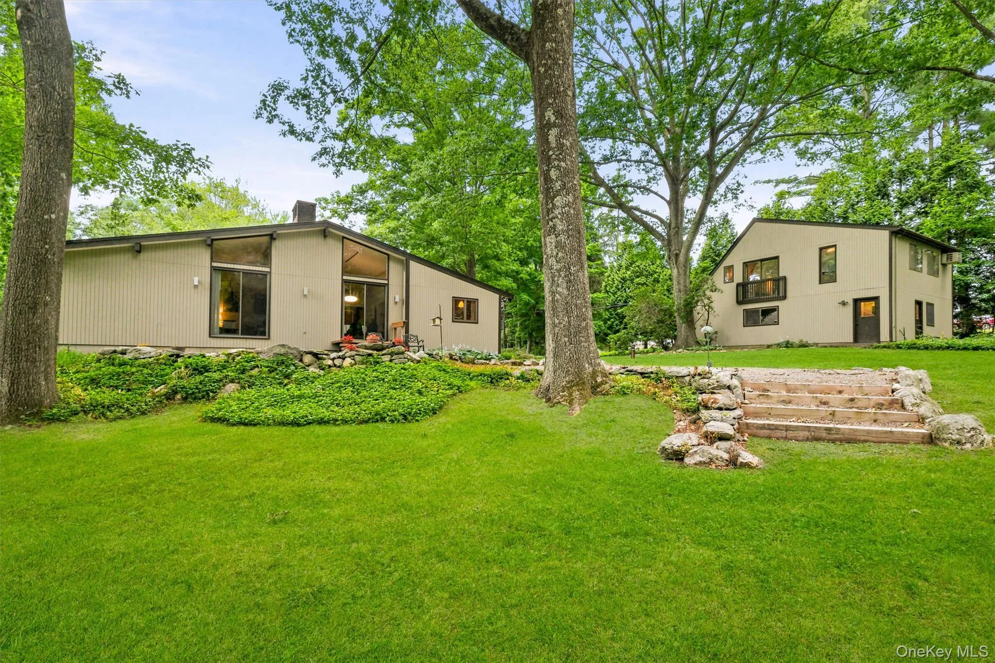 Expansive green lawn with mature trees and a rock-lined stone staircase Expansive green lawn with mature trees and a rock-lined stone staircase