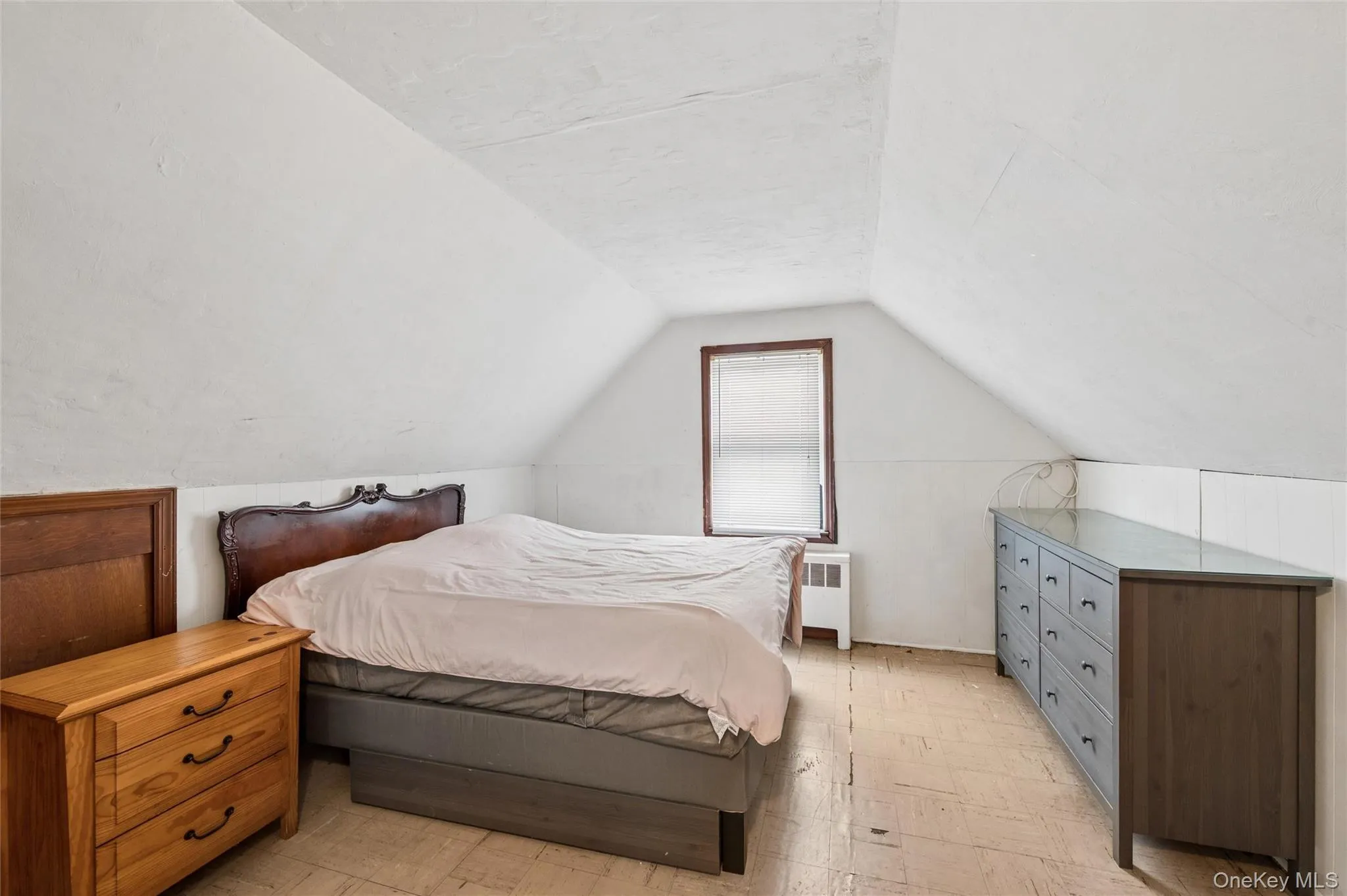 Attic space featuring sloped ceilings, white wall finishes, and a single window with wood trim Attic space featuring sloped ceilings, white wall finishes, and a single window with wood trim
