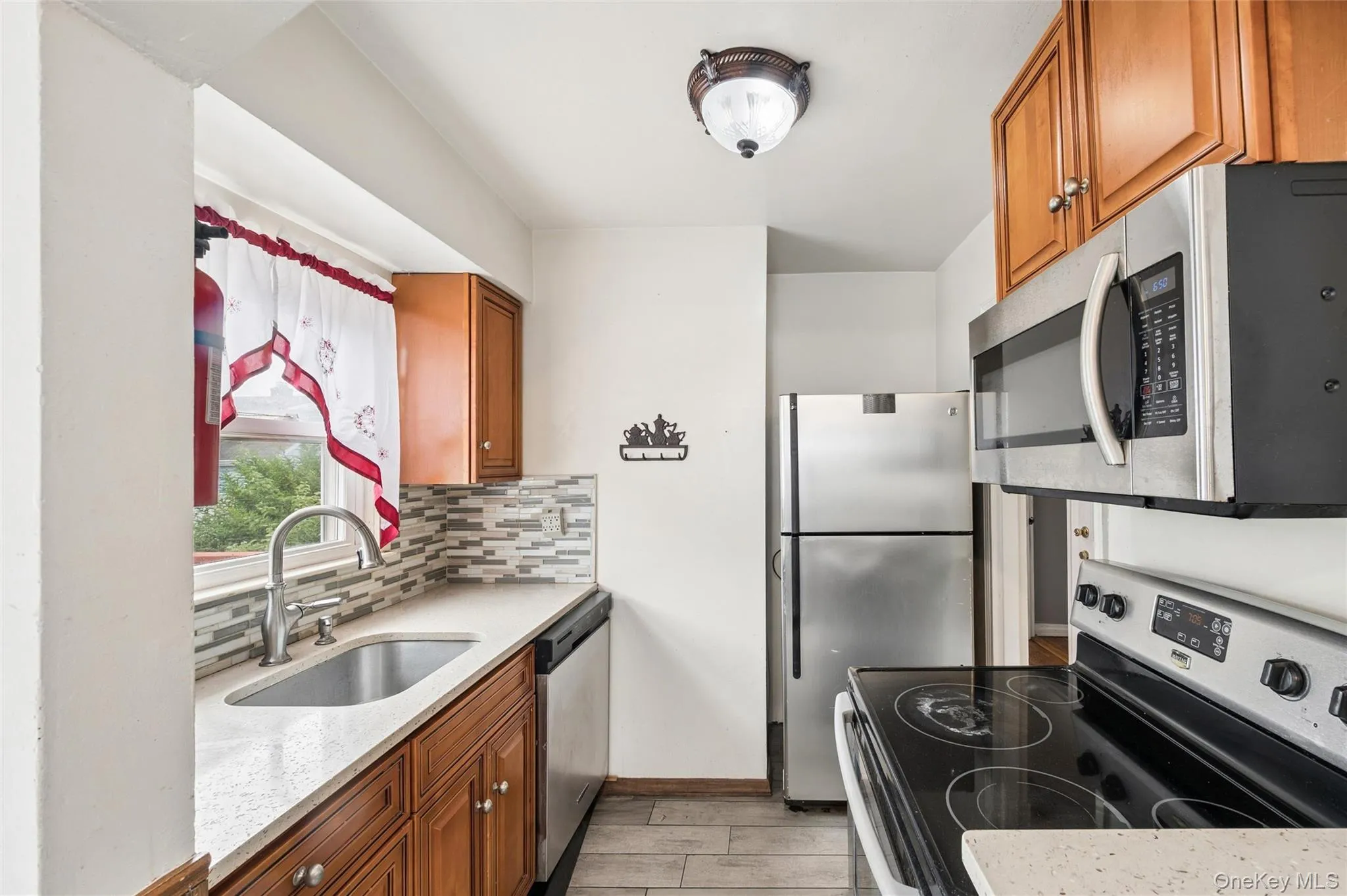 Compact kitchen with wood-finish cabinetry and light-toned countertops Compact kitchen with wood-finish cabinetry and light-toned countertops