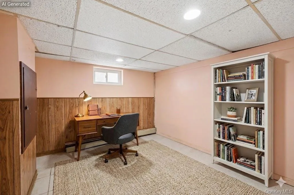 Finished lower level space featuring wood-finish wainscoting, recessed lighting, a drop ceiling, and a window Finished lower level space featuring wood-finish wainscoting, recessed lighting, a drop ceiling, and a window