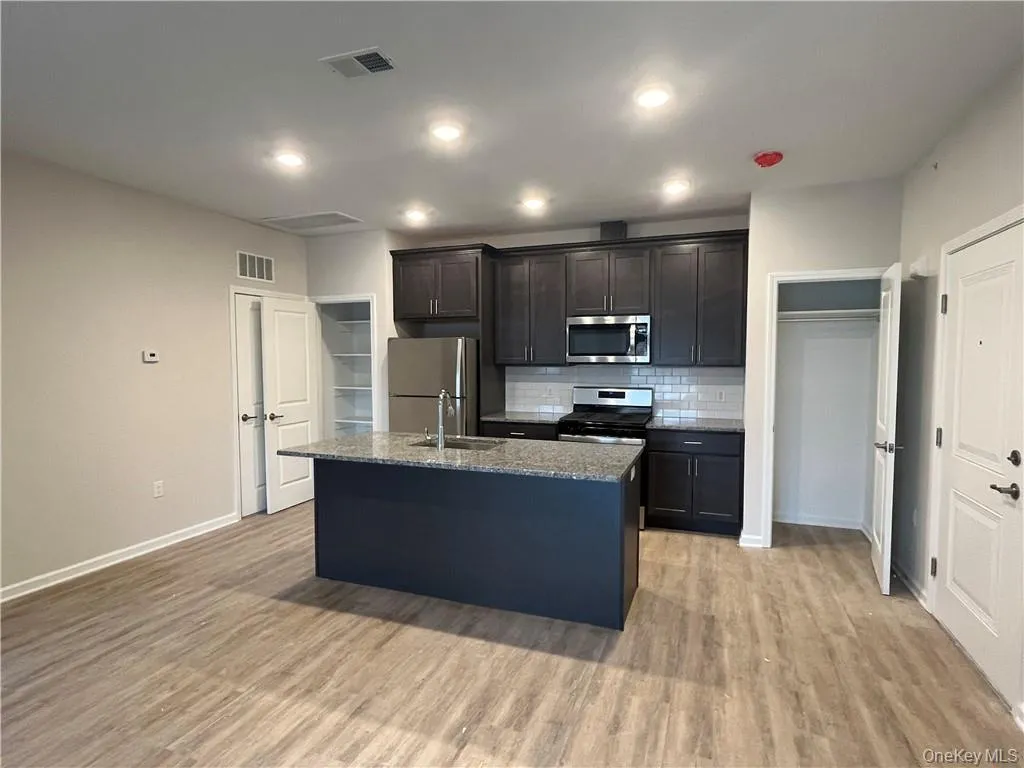 Fully applianced kitchen with stainless steel refrigerator, range, microwave, dishwasher, exterior-vented exhaust hood, pantry closet, recessed lighting, and a spacious center island. Fully applianced kitchen with stainless steel refrigerator, range, microwave, dishwasher, exterior-vented exhaust hood, pantry closet, recessed lighting, and a spacious center island.