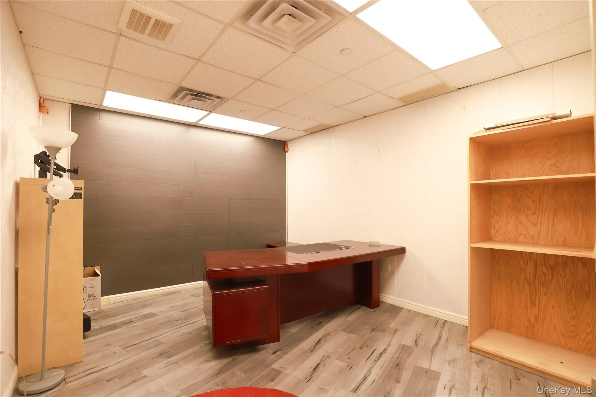 Office space featuring wood-finish flooring, white walls, and a drop-tile ceiling with integrated lighting Office space featuring wood-finish flooring, white walls, and a drop-tile ceiling with integrated lighting