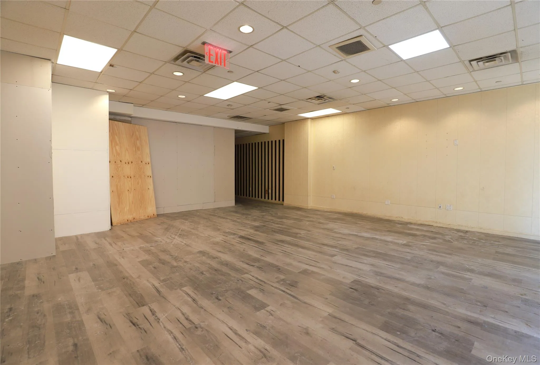 Spacious interior featuring wood-finish flooring, drop ceiling with recessed lighting, and a neutral color palette Spacious interior featuring wood-finish flooring, drop ceiling with recessed lighting, and a neutral color palette