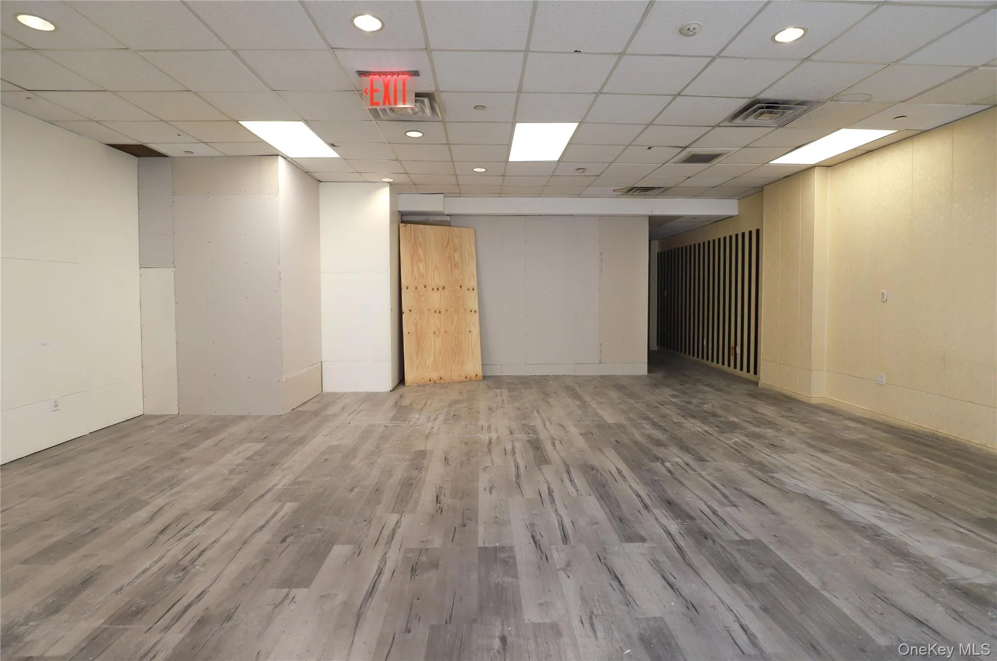 Spacious open-concept interior featuring wood-finish flooring, recessed lighting, and a suspended acoustic ceiling Spacious open-concept interior featuring wood-finish flooring, recessed lighting, and a suspended acoustic ceiling