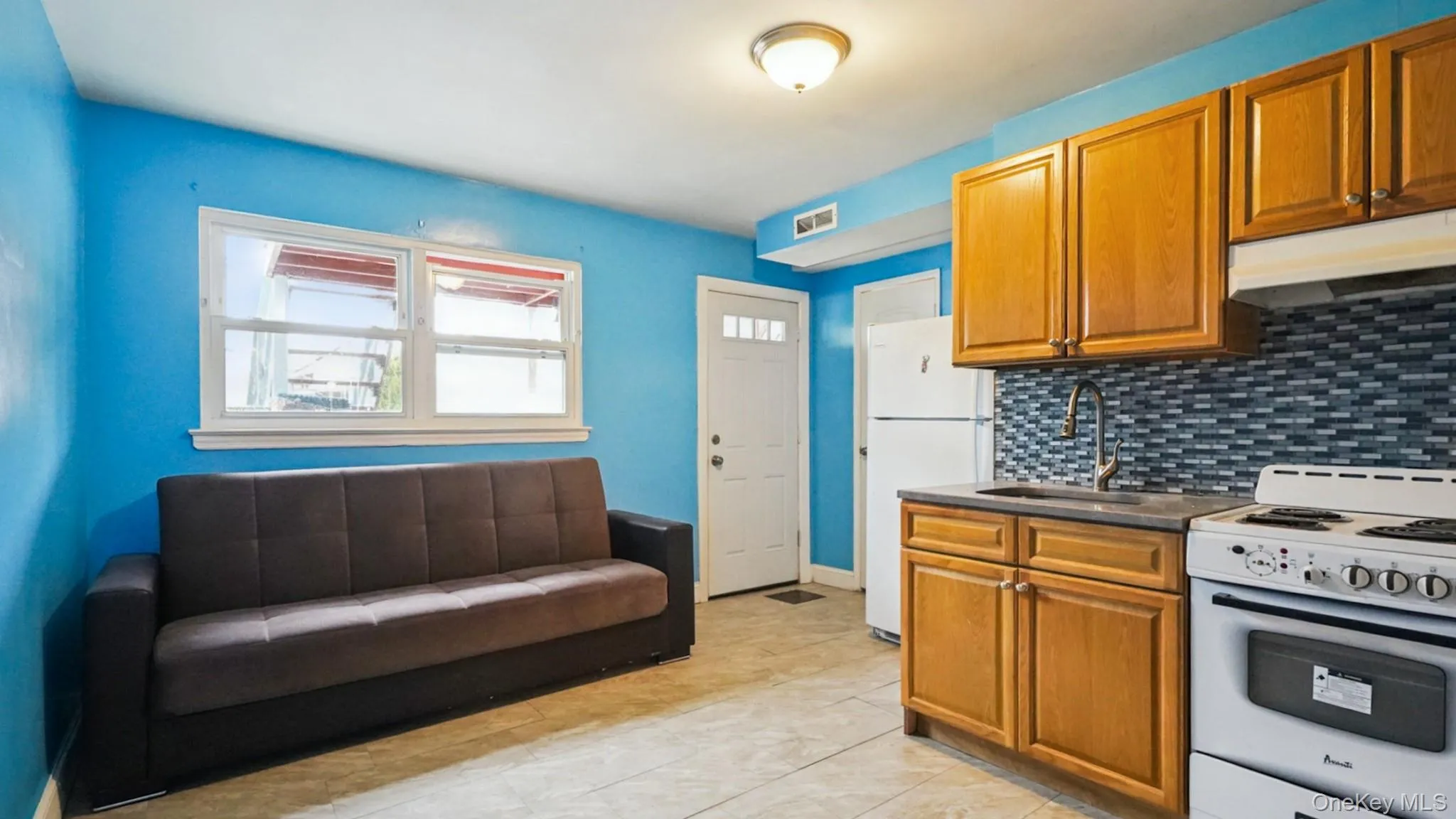Open-concept living space featuring a full kitchen with wood cabinetry, a mosaic tile backsplash, and a white oven/range Open-concept living space featuring a full kitchen with wood cabinetry, a mosaic tile backsplash, and a white oven/range