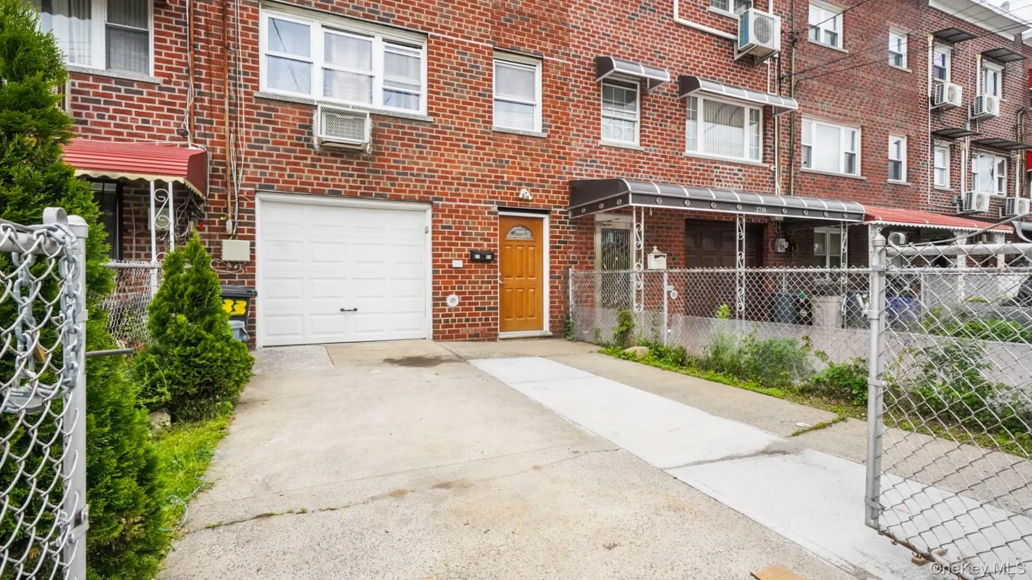 Brick facade residence featuring a white garage door, concrete driveway, and covered front entry Brick facade residence featuring a white garage door, concrete driveway, and covered front entry